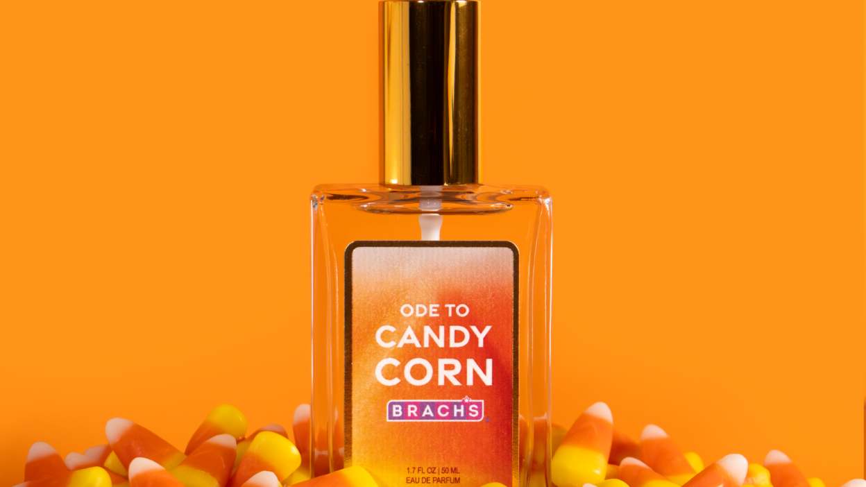 Brach’s Ode to Candy Corn eau de parfum bottle surrounded by candy corn against an orange background.