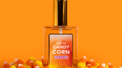 Brach’s Ode to Candy Corn eau de parfum bottle surrounded by candy corn against an orange background.